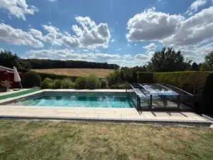 Kundenprojekt von Glocke Pool: Gartenpool mit flacher, zurückgeschobener Poolüberdachung im Spätsommer